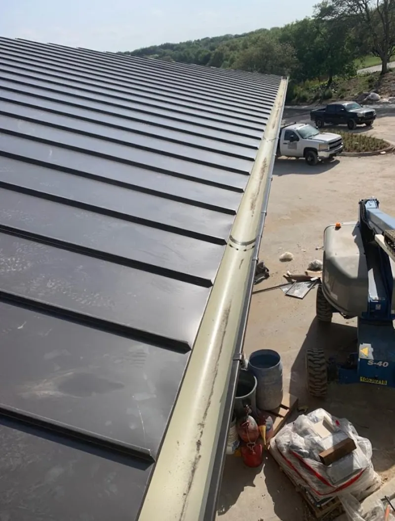 Standing seam panel and gutter detail on a metal roofing jobsite in Watertown
